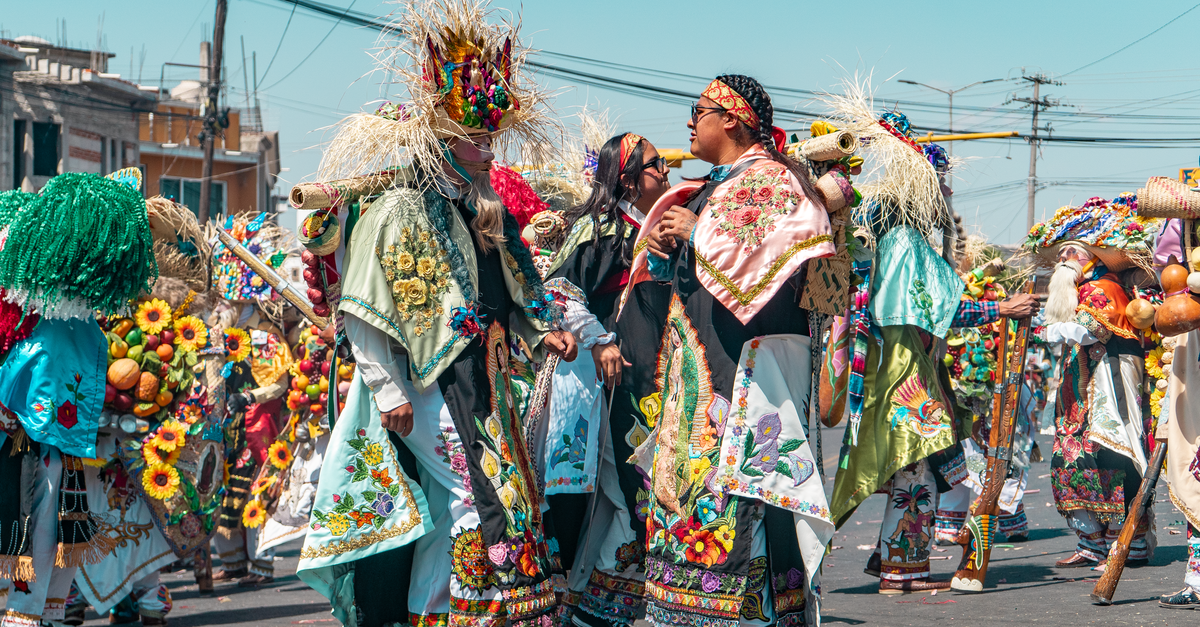 Colorful traditional street festival with people in elaborate costumes celebrating outdoors.